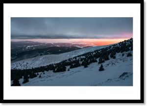 Photographie d’un tirage d’art représentant un coucher de soleil enneigé, illustration de la boutique en ligne.